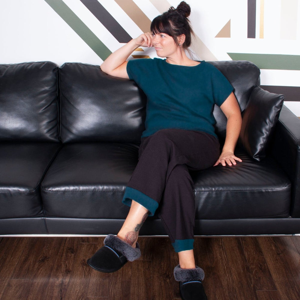 Women Wearing Aqua and Black Bamboo Pajama Pants and T-Shirt Sitting on a Sofa